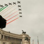 Formazione di aerei delle Frecce Tricolori che vola sopra l’Altare della Patria a Roma lasciando scie di fumo verde, bianco e rosso nel cielo.
