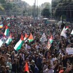 Folla numerosa a Roma con bandiere palestinesi e striscioni durante una manifestazione pro Palestina.