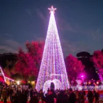Grande albero di Natale luminoso e folla di visitatori durante l’evento Christmas World a Villa Borghese, Roma