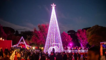 Grande albero di Natale luminoso e folla di visitatori durante l’evento Christmas World a Villa Borghese, Roma