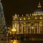 Piazza San Pietro illuminata per Natale, con l’albero decorato e la basilica sullo sfondo di notte.