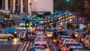 Traffico intenso a Roma con lunghe code di auto e motorini vicino al centro, in una strada affollata al tramonto.