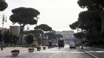 Vista dei Fori Imperiali chiusi al traffico con operai e mezzi al lavoro, Colosseo sullo sfondo.