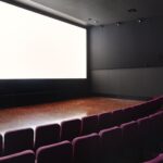 Interno della sala del Cinema Troisi con schermo luminoso e poltrone viola disposte a semicerchio.