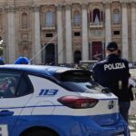 Agenti di polizia e auto di servizio davanti alla Basilica di San Pietro durante un controllo di sicurezza.