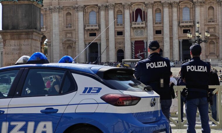 Agenti di polizia e auto di servizio davanti alla Basilica di San Pietro durante un controllo di sicurezza.