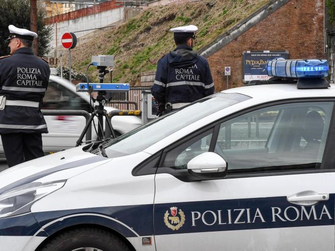 Agenti della Polizia Locale di Roma Capitale controllano il traffico con dispositivi elettronici vicino a una pattuglia.