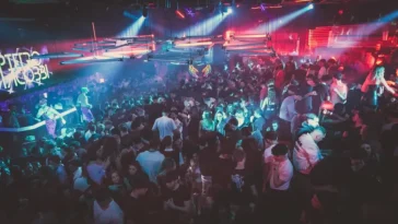 Folla in una discoteca romana illuminata da luci colorate durante una serata affollata.