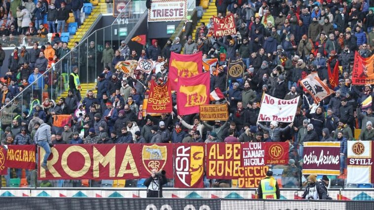 Tifosi della Roma sugli spalti con bandiere e striscioni giallorossi durante una trasferta.