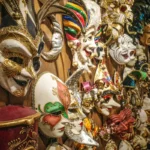 Maschera di Carnevale rosa e oro appoggiata su un tavolo con stelle filanti colorate.