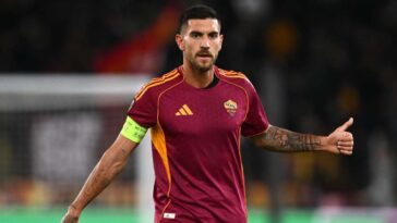 Calciatore della Roma con fascia da capitano durante una partita, in maglia giallorossa, mentre fa un gesto con il braccio.