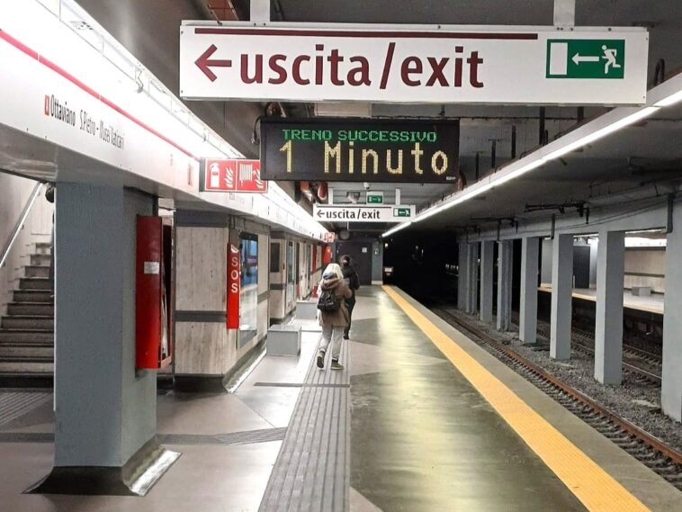 Banchina della metro A di Ottaviano con passeggeri e cartelli di uscita.