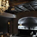Interno del night club Escopazzo con lampadario a gocce, soffitto in legno e bancone illuminato.