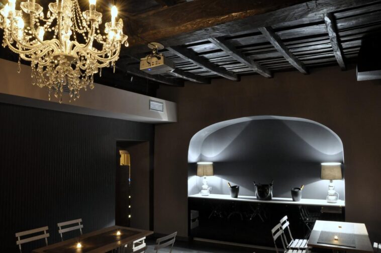 Interno del night club Escopazzo con lampadario a gocce, soffitto in legno e bancone illuminato.