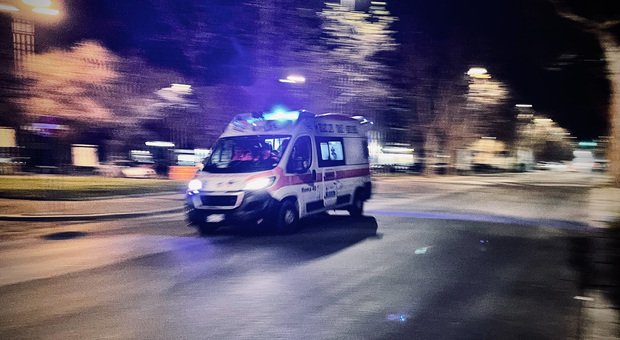 Ambulanza in corsa di notte con sirene accese su una strada urbana semideserta.