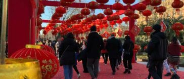 Lantern festival del Capodanno Cinese a piazza Vittorio, con persone che camminano sotto decine di lanterne rosse appese nelle strutture decorative.