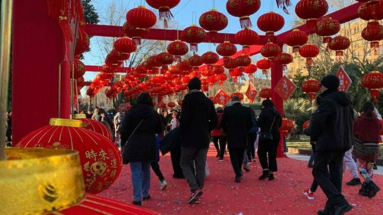 Lantern festival del Capodanno Cinese a piazza Vittorio, con persone che camminano sotto decine di lanterne rosse appese nelle strutture decorative.