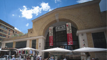 Facciata del Mercato Nomentano a Roma con bancarelle e visitatori all’esterno.