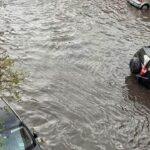 Strada completamente allagata con auto semisommerse dopo un violento nubifragio.