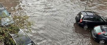 Strada completamente allagata con auto semisommerse dopo un violento nubifragio.