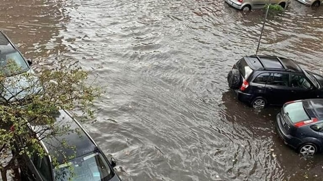 Strada completamente allagata con auto semisommerse dopo un violento nubifragio.