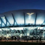 Rendering notturno del nuovo Stadio Flaminio illuminato con il logo della Lazio sulla facciata.