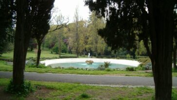Veduta della fontana ovale di Villa Borghese circondata da alberi e sentieri, in un’area tranquilla del parco.