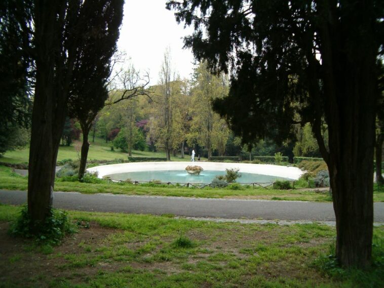 Veduta della fontana ovale di Villa Borghese circondata da alberi e sentieri, in un’area tranquilla del parco.