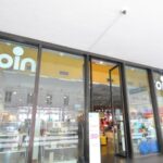 Ingresso del negozio Coin di via Giolitti a Roma, con vetrate e cartelli promozionali visibili dall’esterno.