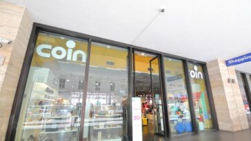 Ingresso del negozio Coin di via Giolitti a Roma, con vetrate e cartelli promozionali visibili dall’esterno.