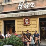 ingresso del Bar San Calisto a Trastevere con clienti seduti all’esterno.