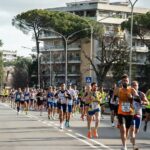 Atleti in corsa durante la Roma-Ostia su una strada chiusa al traffico.