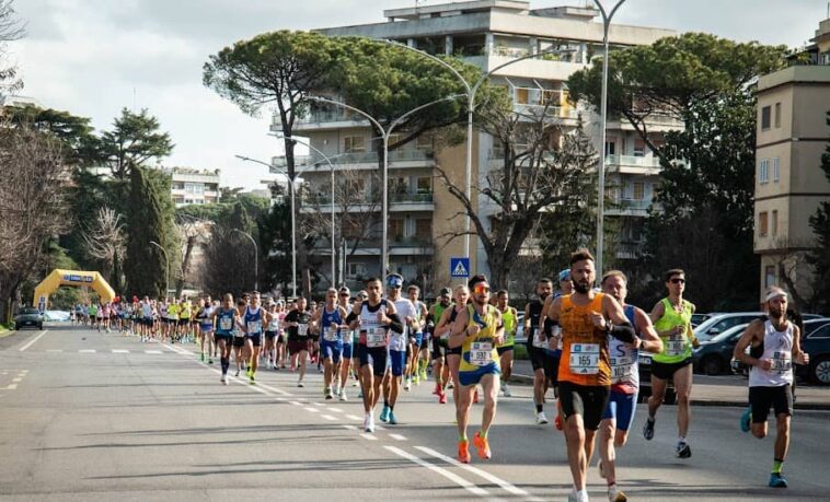 Atleti in corsa durante la Roma-Ostia su una strada chiusa al traffico.