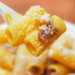 Primo piano di un piatto di carbonara con rigatoni, guanciale croccante e pecorino durante il festival a Roma Ostiense.