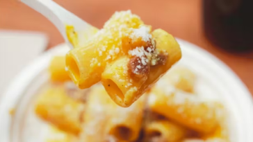 Primo piano di un piatto di carbonara con rigatoni, guanciale croccante e pecorino durante il festival a Roma Ostiense.