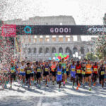 Runner alla partenza della Maratona di Roma davanti al Colosseo con coriandoli e arco di partenza.