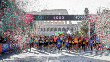 Runner alla partenza della Maratona di Roma davanti al Colosseo con coriandoli e arco di partenza.
