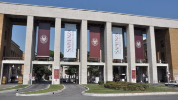 Ingresso monumentale dell’Università La Sapienza di Roma con colonne e banner ufficiali.