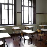 Aula scolastica vuota con banchi distanziati e grandi finestre in una scuola di Roma.