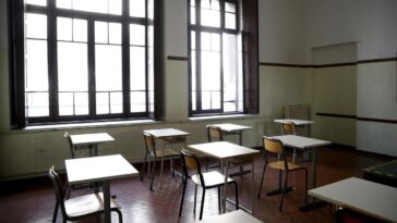 Aula scolastica vuota con banchi distanziati e grandi finestre in una scuola di Roma.