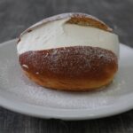 Maritozzo con panna montata su piattino bianco, dolce tipico della colazione romana