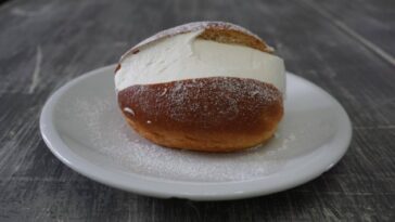 Maritozzo con panna montata su piattino bianco, dolce tipico della colazione romana