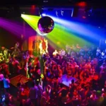 Discoteca affollata con luci colorate e pista da ballo piena di persone