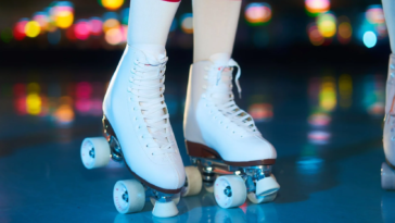 Pattini a rotelle bianchi indossati su una pista illuminata con luci colorate in stile discoteca