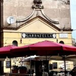 Il bar dei Cesaroni alla Garbatella con insegna storica e tavolini all’aperto in piazza Giovanni da Triora