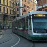 Tram in servizio nel centro di Roma lungo i binari tra palazzi storici e strade urbane trafficate.