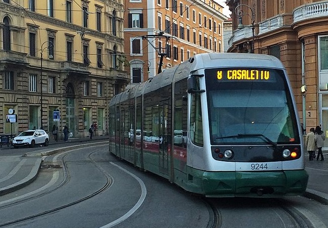 Tram in servizio nel centro di Roma lungo i binari tra palazzi storici e strade urbane trafficate.