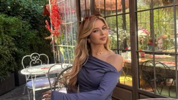 Ragazza giovane posa in un giardino con abito elegante e sfondo floreale.