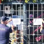 Agenti della Polizia affiggono i sigilli di chiusura su un locale a Roma.