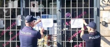 Agenti della Polizia affiggono i sigilli di chiusura su un locale a Roma.